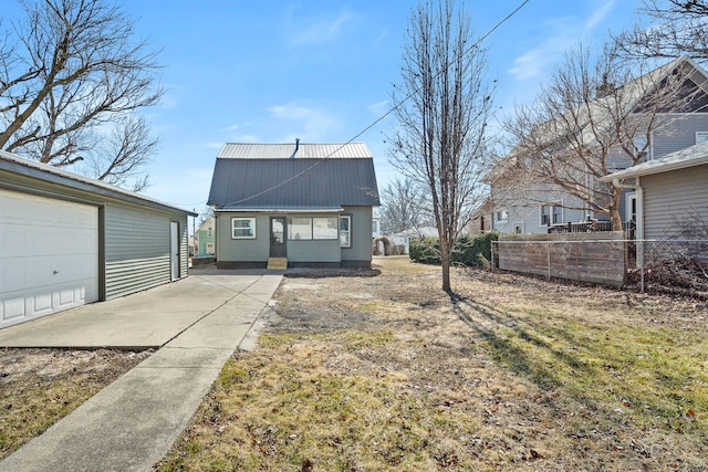 rear view of house with metal roof, an outbuilding, and fence