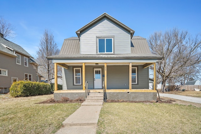 view of front facade with a porch, metal roof, a front yard, and fence