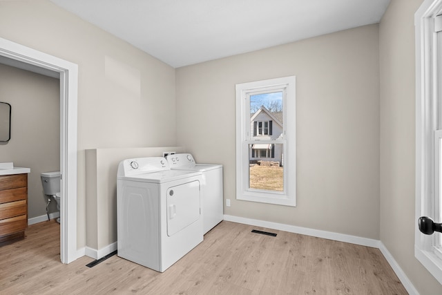 laundry area featuring visible vents, washer and dryer, light wood-type flooring, and baseboards