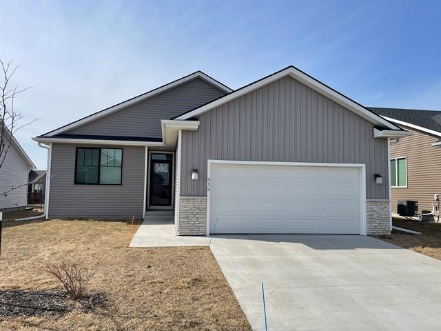 ranch-style home featuring stone siding, an attached garage, and driveway