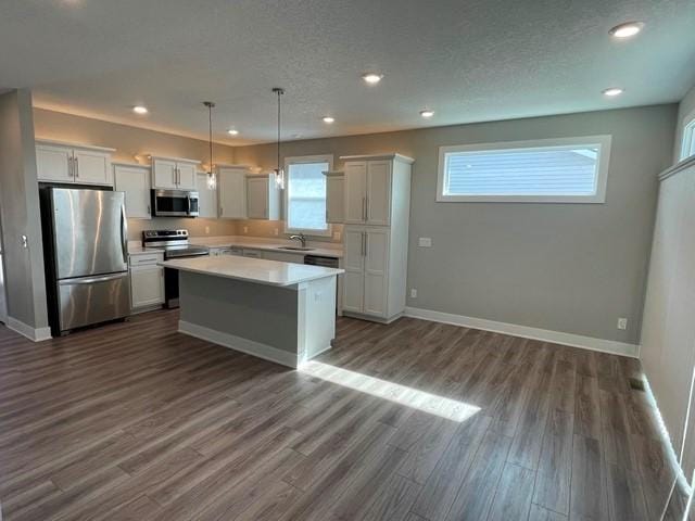 kitchen with dark wood-type flooring, baseboards, light countertops, stainless steel appliances, and a sink