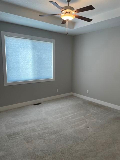 spare room featuring carpet, baseboards, visible vents, and ceiling fan