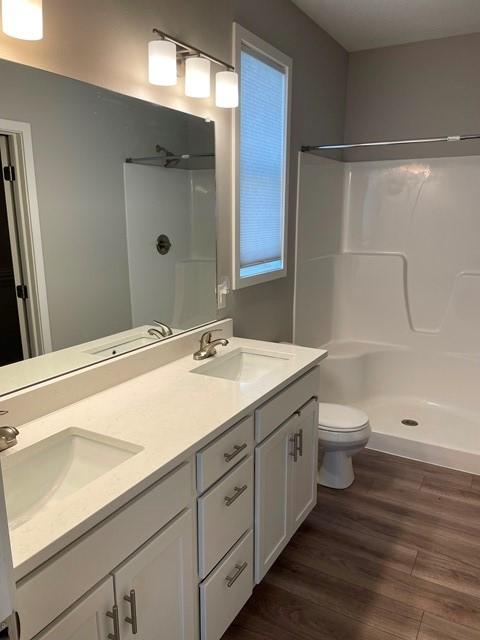 full bathroom with wood finished floors, walk in shower, and a sink