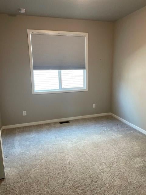 empty room with visible vents, baseboards, and carpet