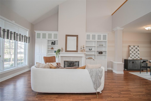 living area with a fireplace, dark wood-style floors, baseboards, and ornate columns