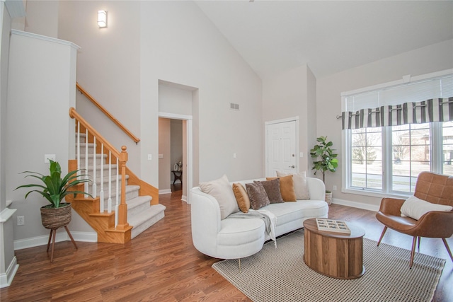 living room featuring visible vents, high vaulted ceiling, wood finished floors, and stairway