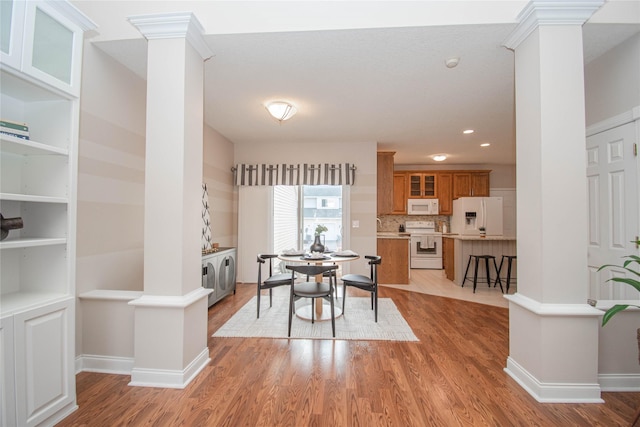 dining room with light wood finished floors, baseboards, and ornate columns