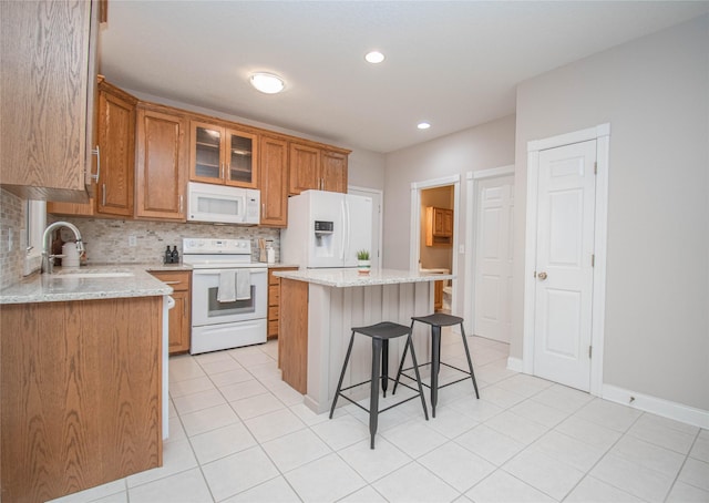 kitchen featuring a kitchen bar, a sink, a kitchen island, white appliances, and decorative backsplash