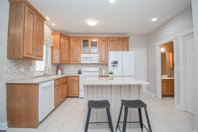 kitchen with decorative backsplash, white appliances, light tile patterned floors, and a sink