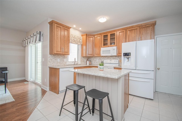 kitchen with light tile patterned floors, glass insert cabinets, white appliances, and a sink