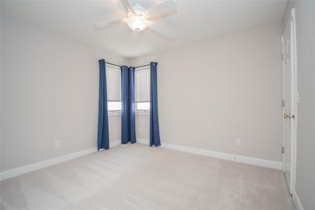 unfurnished room with light colored carpet, a ceiling fan, and baseboards