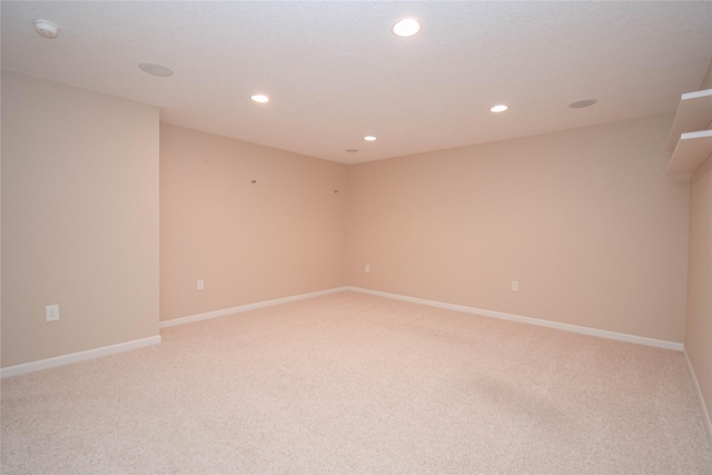 empty room featuring light carpet, recessed lighting, and baseboards