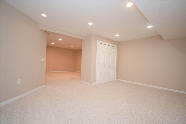 finished below grade area with recessed lighting, light colored carpet, baseboards, and a textured ceiling