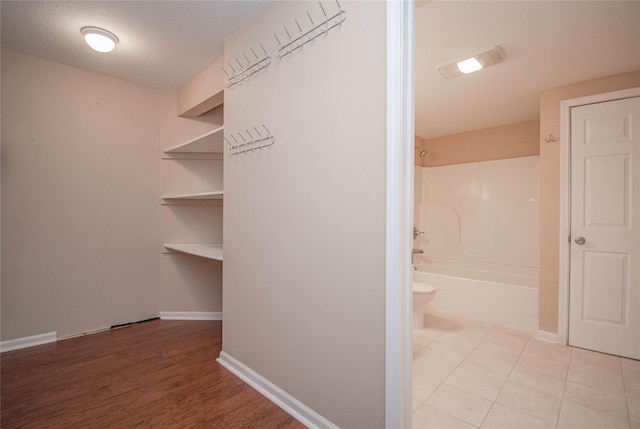 interior space with light tile patterned floors, baseboards, and a textured ceiling