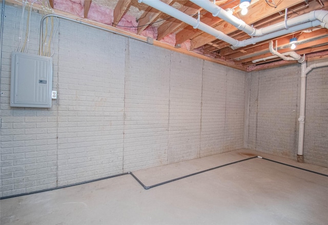 unfinished basement featuring electric panel and brick wall