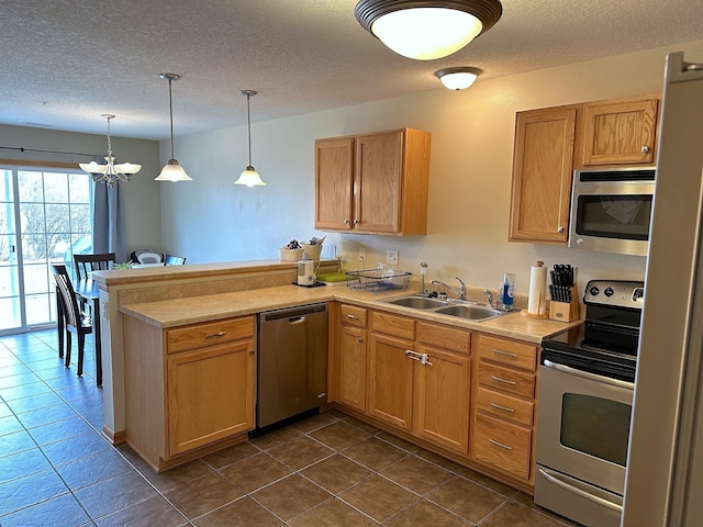 kitchen with a peninsula, a sink, stainless steel appliances, light countertops, and a notable chandelier