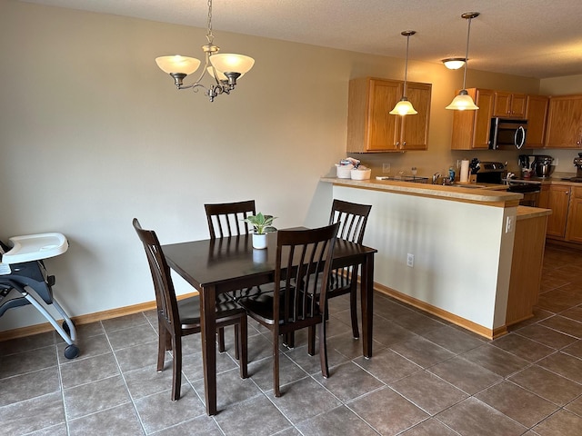 dining space featuring baseboards, a notable chandelier, and dark tile patterned floors