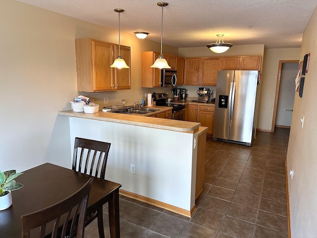 kitchen with pendant lighting, dark tile patterned floors, stainless steel appliances, a peninsula, and light countertops