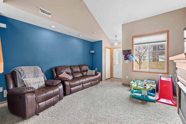 carpeted living room with visible vents, a fireplace, high vaulted ceiling, and baseboards