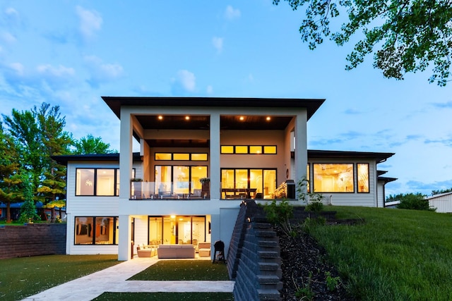 rear view of property with a lawn, a balcony, stairs, and a patio area