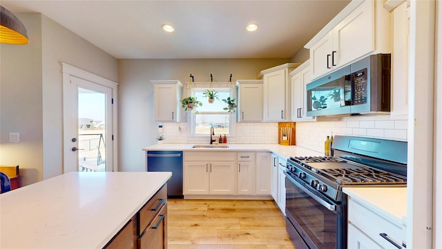 kitchen with stainless steel microwave, dishwasher, light countertops, range with gas stovetop, and a sink