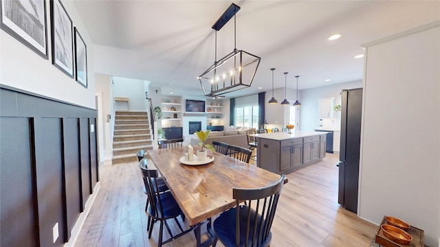 dining space featuring built in shelves, stairs, recessed lighting, light wood-style flooring, and a fireplace