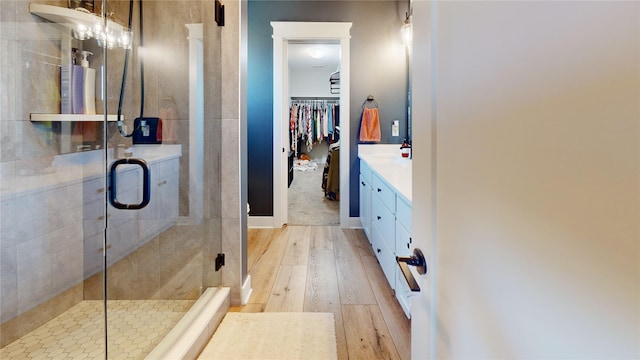 bathroom with vanity, a shower stall, a walk in closet, and wood finished floors