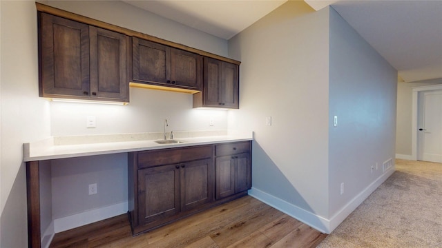 kitchen featuring visible vents, a sink, light countertops, baseboards, and dark brown cabinets