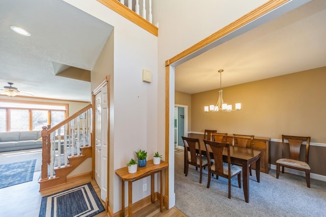 dining area featuring baseboards, stairs, and ceiling fan with notable chandelier