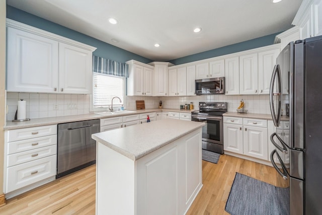 kitchen featuring light wood-style flooring, appliances with stainless steel finishes, white cabinets, and a sink