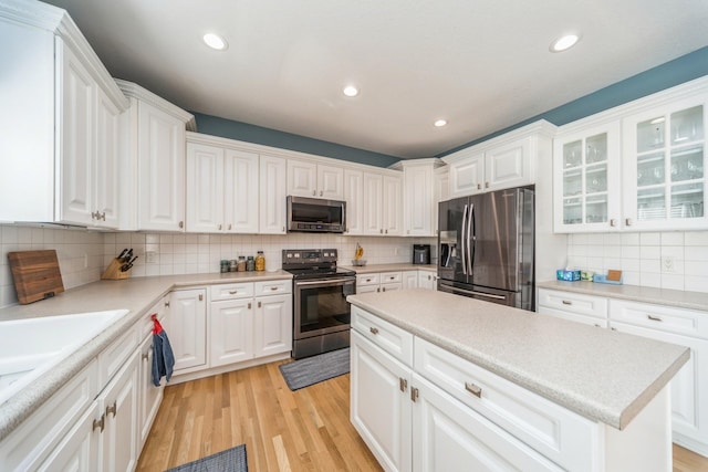 kitchen with light wood-type flooring, light countertops, recessed lighting, appliances with stainless steel finishes, and white cabinetry