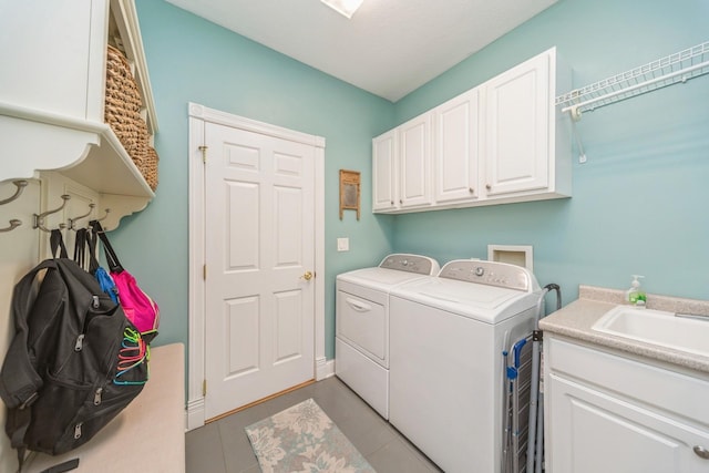 washroom with light tile patterned floors, cabinet space, independent washer and dryer, and a sink