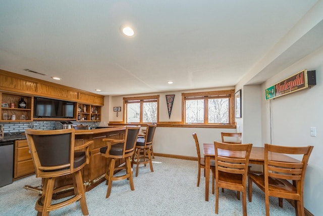 dining space featuring visible vents, plenty of natural light, baseboards, and indoor bar