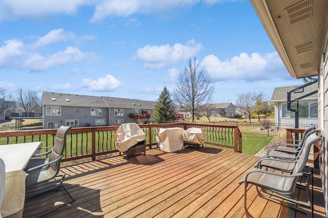 wooden terrace with a residential view, a yard, and fence