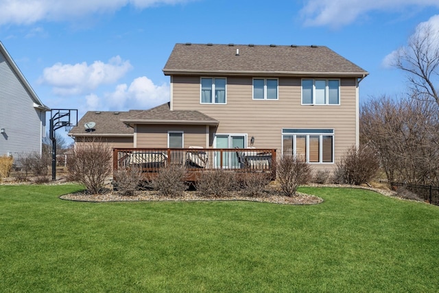 rear view of house with a deck, a yard, and a shingled roof