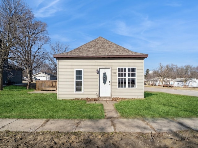 exterior space featuring roof with shingles and a front yard