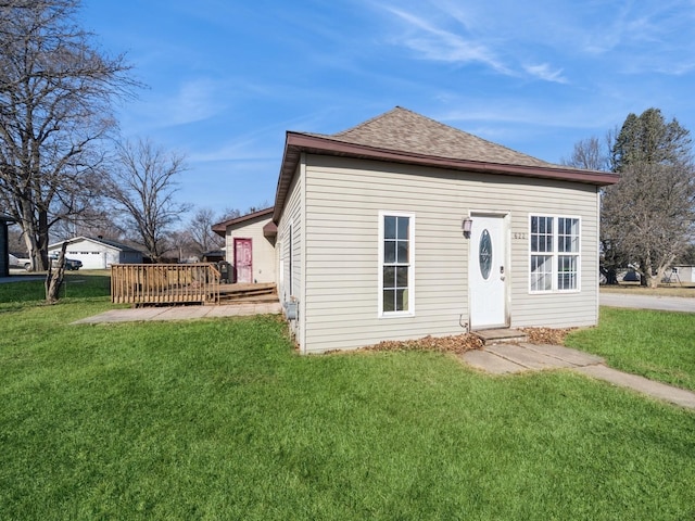 view of front of property featuring a deck, a front yard, and a shingled roof