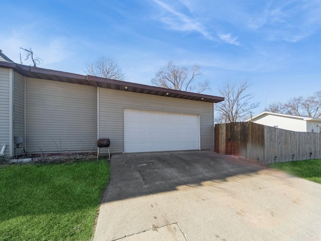 garage featuring concrete driveway and fence