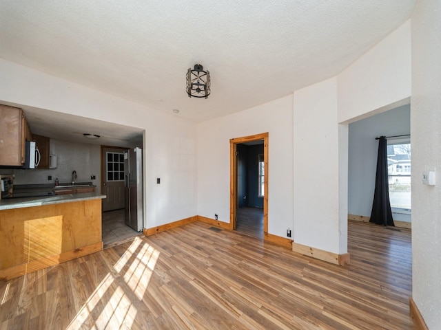 kitchen with stainless steel appliances, light wood-type flooring, baseboards, and a sink