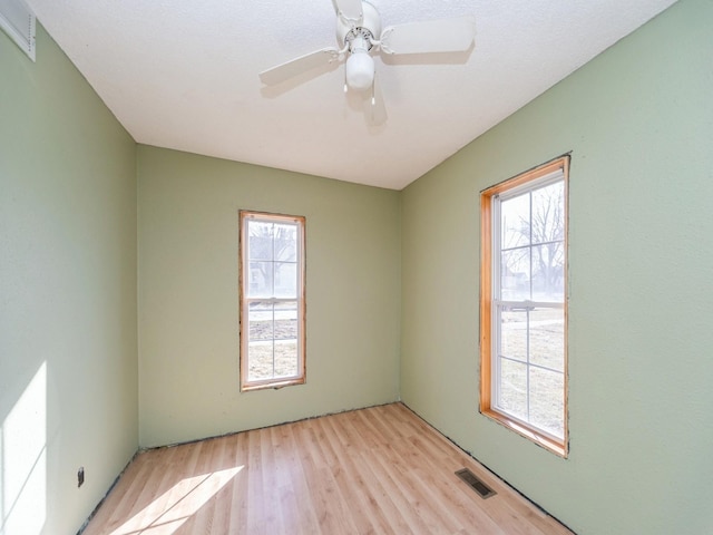 unfurnished room with light wood-style flooring, visible vents, and ceiling fan