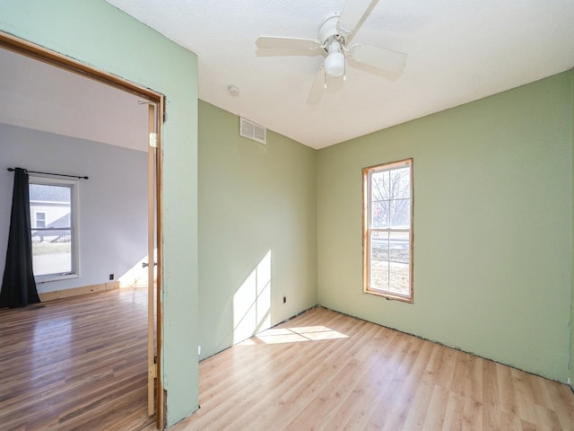 spare room featuring visible vents, wood finished floors, and a ceiling fan