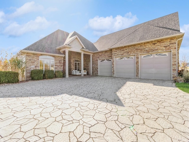 view of front facade with decorative driveway, a garage, and roof with shingles