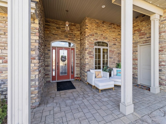 doorway to property featuring covered porch and stone siding