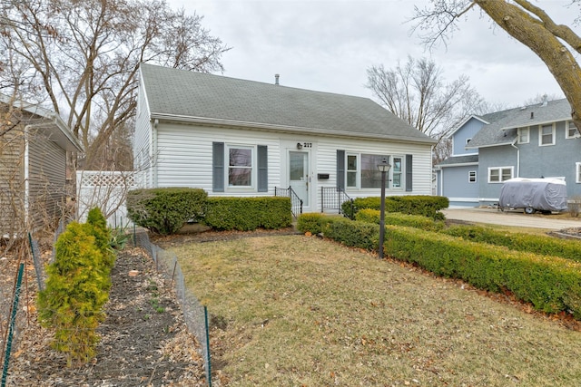 view of front of property with roof with shingles, a front lawn, and fence