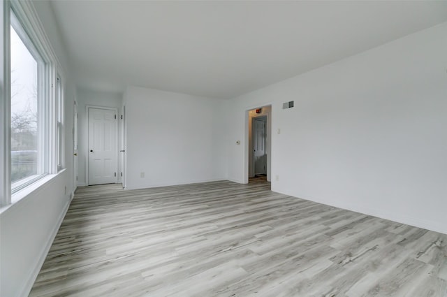 spare room featuring light wood finished floors and visible vents