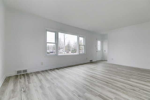 unfurnished living room featuring visible vents, baseboards, and wood finished floors