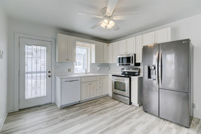 kitchen with light wood finished floors, a sink, stainless steel appliances, light countertops, and white cabinets