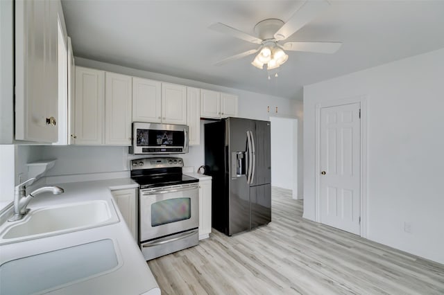 kitchen with a ceiling fan, a sink, stainless steel appliances, light countertops, and white cabinetry