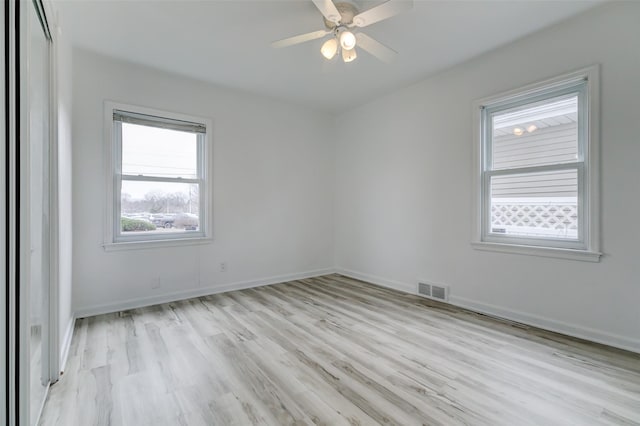 spare room featuring visible vents, light wood-style flooring, a ceiling fan, and baseboards