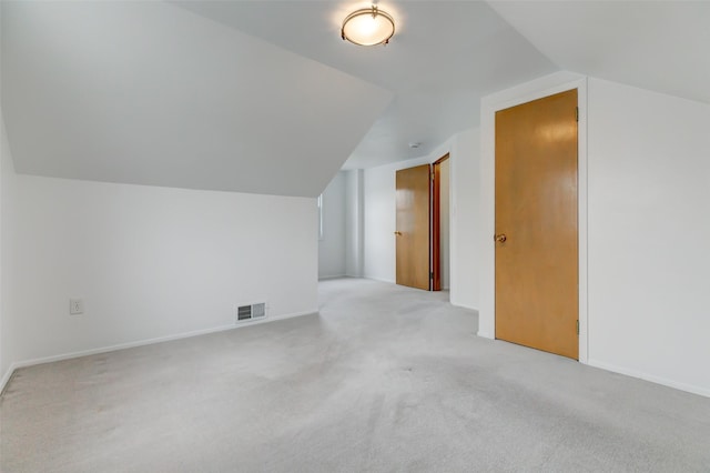 bonus room featuring visible vents, light carpet, baseboards, and vaulted ceiling